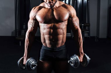 Atlet spor salonunda elinde dumbbells ile