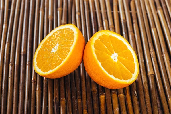 Две половины апельсина на бамбуковом фоне — стоковое фото