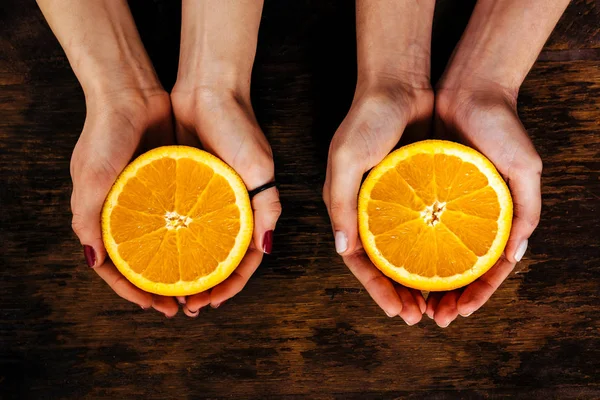 Девушка с половиной апельсина на деревянном столе — стоковое фото