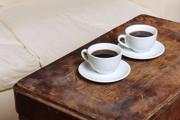Dois cafés expresso em pequenas xícaras brancas descansando sobre o fundo de madeira — Fotografia de Stock