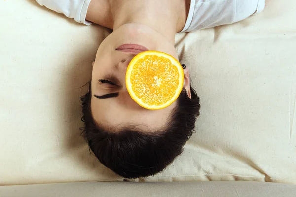 The girl is with a piece of orange on the eye — Stock Photo, Image