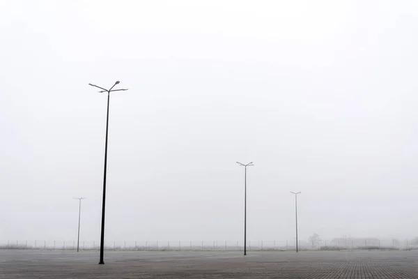 Фонари на пустынной парковке в тумане — стоковое фото