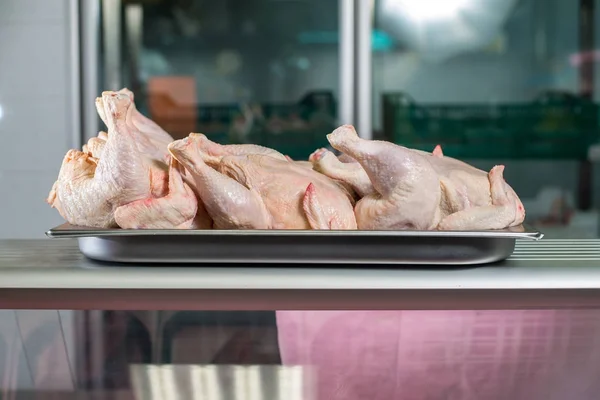 Raw whole chicken in profile on the  iron tray