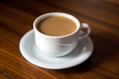 Tahta bir masada sütlü bir fincan kahve.