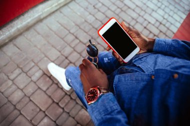 Bir genç adam sokakta bir cep telefonu