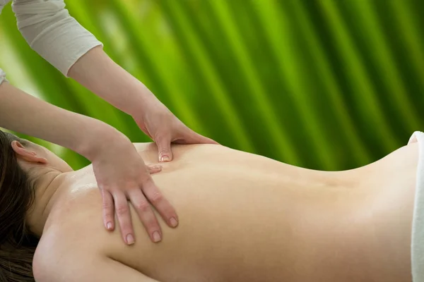 Mãos de massagista em um fundo verde — Fotografia de Stock