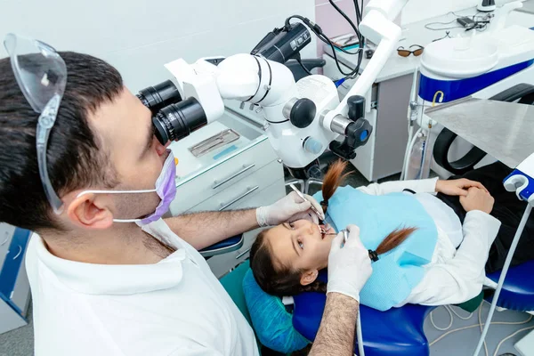 Il dentista esamina i denti del bambino con un microscopio. Attrezzature dentali professionali — Foto Stock