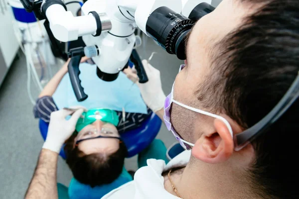 Der Zahnarzt untersucht die Zähne mit dem Mikroskop — Stockfoto