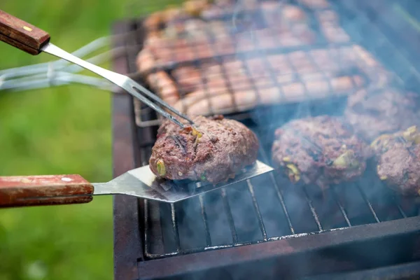 Homemade meat for burgers. Man cooks on the grill