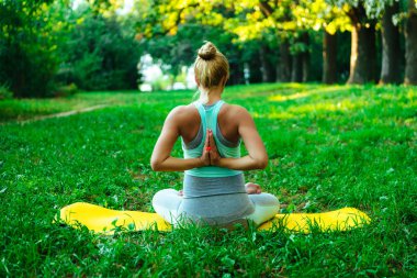 Genç hamile kız parkta yoga yapıyor.
