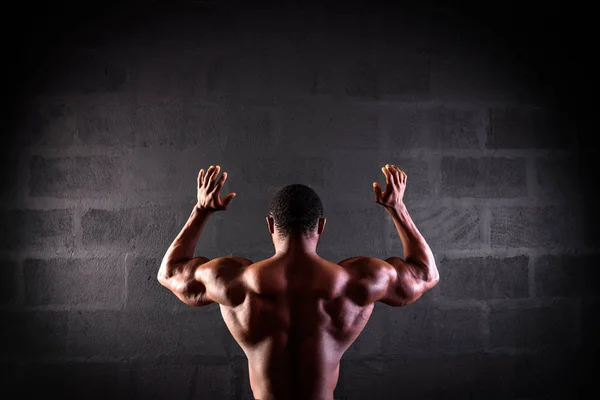 Αφροαμερικανός αθλητής που ποζάρει επιδεικνύοντας ανεπτυγμένους μυς της πλάτης και των χεριών — Φωτογραφία Αρχείου