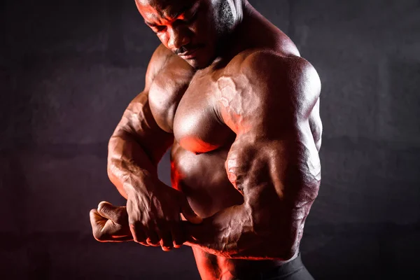 Gros plan sur un bodybuilder. Athlète masculin afro-américain posant démontrant le développement musculaire des bras biceps — Photo