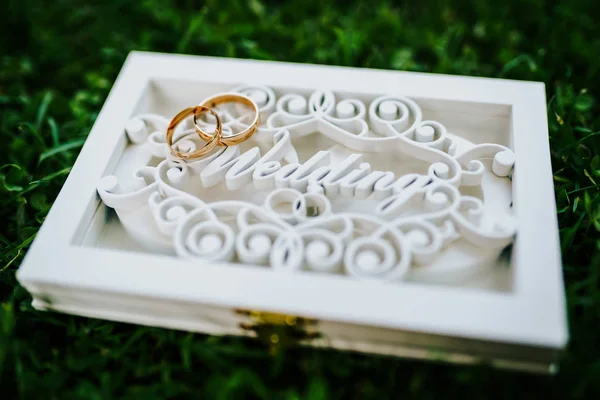 Свадебные кольца в специальной белой коробке с надписью свадьба на зеленой траве — стоковое фото