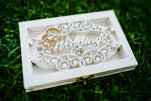 Свадебные кольца в специальной белой коробке с надписью свадьба на зеленой траве — стоковое фото