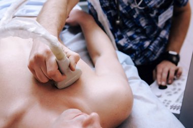 Doktor, klinikteki hastaya kalp ultrasonu yapar.