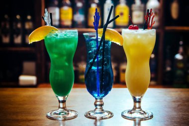 Tahta masadaki bir barda buzlu farklı bir alkollü kokteyl.