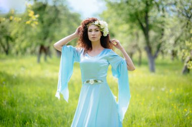 Güzel kız bahar elma bahçesinde duruyor uzun bir elbiseyle