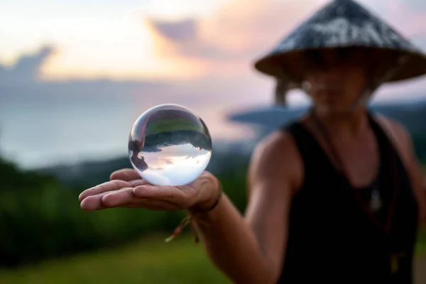 Молодой волшебник держит стеклянный шар для контактного жонглирования на закате — стоковое фото