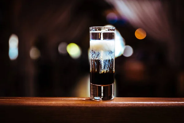 Coquetel de bebida curta em camadas com diferentes tipos de álcool. Bebida alcoólica em um balcão de madeira em um restaurante — Fotografia de Stock
