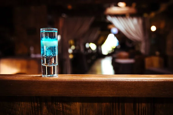 Короткий коктейль в слоях с различными видами алкоголя. Алкогольный напиток на деревянном барной стойке в ресторане — стоковое фото