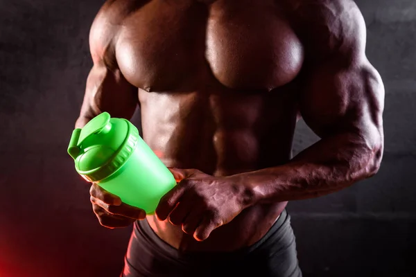 Torso of an African bodybuilder with a shaker in his hands on a black background — 스톡 사진