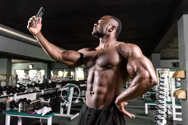 Vücut geliştirici Afrikalı Amerikalı spor blogu için akıllı telefon kullanıyor — Stok fotoğraf