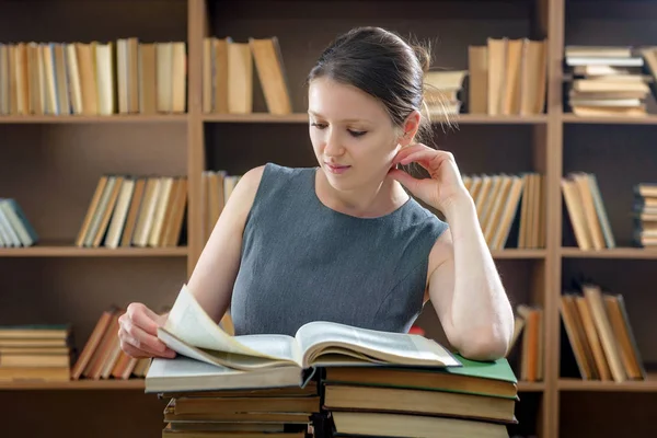 Девушка зачата читает среди старых книг в библиотеке — стоковое фото