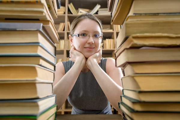 La chica con gafas entre los viejos libros de la biblioteca — Foto de Stock