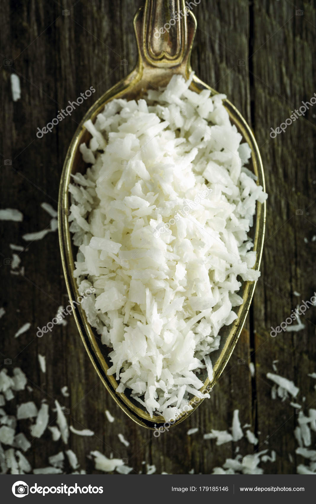Colher de flocos de coco dessecados sobre um fundo de madeira fotos