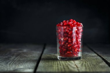 Olgun nar taneleri vintage ahşap arka plan üzerinde küçücük bir cam