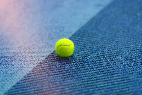 Yellow Tennis ball on bright blue indoor carpet