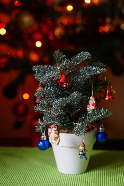 Uma pequena árvore de Natal decorada em vaso na mesa com luz — Fotografia de Stock