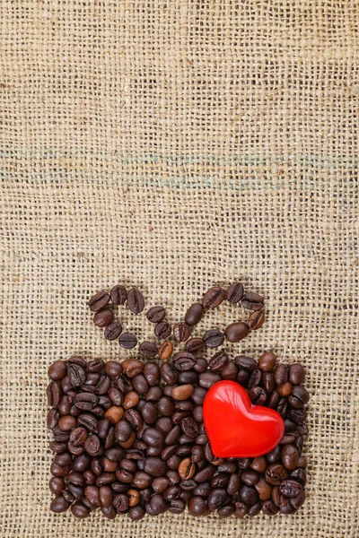 Present made of coffee beans on sackcloth with red heart — Stock Photo, Image