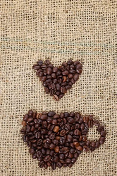 Geröstete Kaffeebohnen in Form einer Tasse platziert und auf — Stockfoto