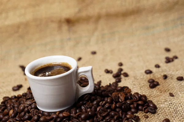 Taza de café en saco con granos de café — Foto de Stock