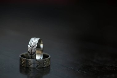 Koyu ahşap yüzeyde iki alyans ve bulanık bir arka plan.