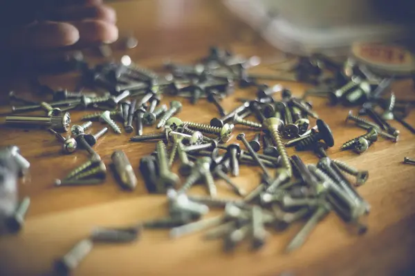 Different types and sizes of nails and screws on a wooden table — Stock Photo, Image