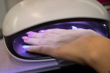 Kadınlar oje kurutma makinesini manikürcüye verdiler.