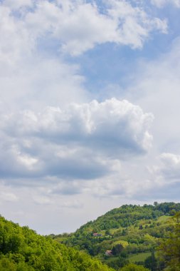 Tepenin tepesinde birkaç hortum, orman ve bulutlu mavi gökyüzü.