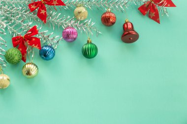 Oyuncak toplarının Noel kompozisyonu gümüş ağaç dallarından sarkan nane arkaplanındaki çan süslerini selamlıyor..