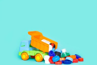 Kamyon plastik kapakları, ayrı çöp ve atık geri dönüşümü kavramını, mavi arka planda fotokopi alanı olan oyuncakları fırlatıyor