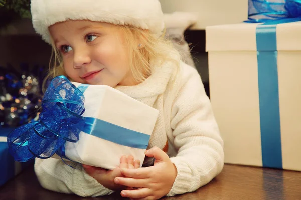 Kleines Mädchen mit Weihnachtsmütze und Geschenk — Stockfoto