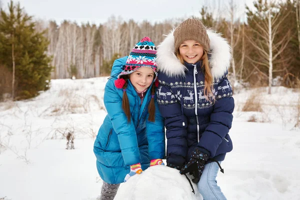 Zwei Freundinnen bauen einen Schneemann — Stockfoto