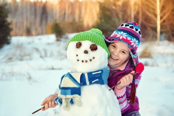 Garoto feliz brincando com boneco de neve — Fotografia de Stock