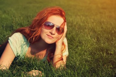 Kızıl saçlı kız çimenlerin üzerinde rahatlatıcı