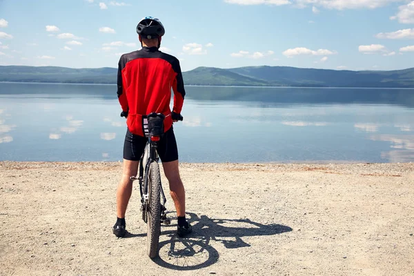 Ciclista na margem de um lago de montanha — Fotografia de Stock