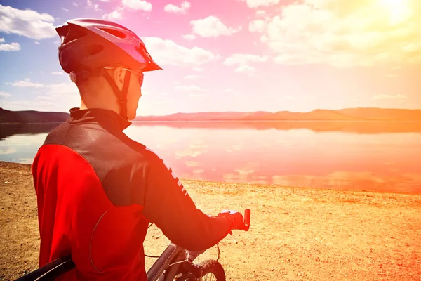 Cyclist on the shore of a mountain lake — Stock Photo, Image