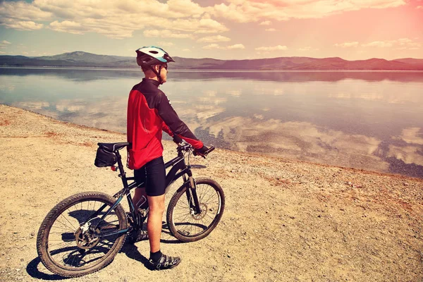 Cyclist on the shore of a mountain lake — Stock Photo, Image