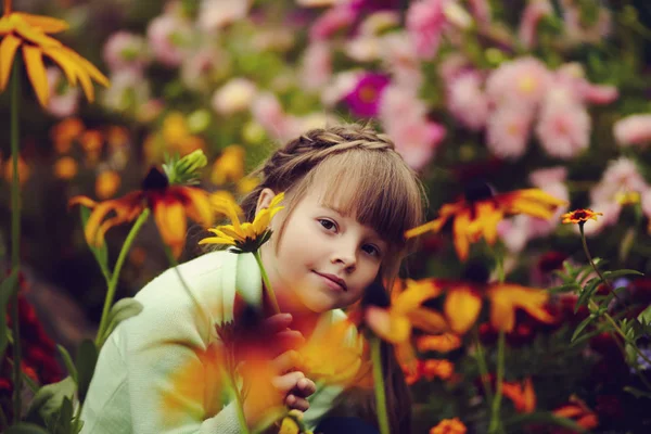 Kleines Mädchen im Garten mit Blumen — Stockfoto