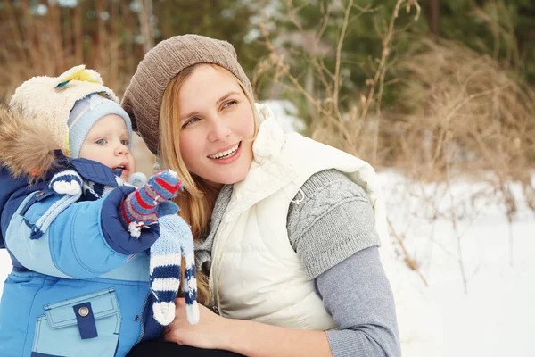 幸せな母と冬の公園で赤ちゃん。屋外の家族。彼女は子供に陽気なママ. — ストック写真